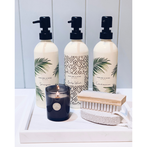 Shampoo, conditioner bottles with palm print against cream background. Body wash has geometric style pattern